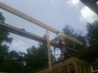 Carpenter setting a ridge beam over a new addition frame — Ice Dam Removal by Roofing Brothers in Whitharral