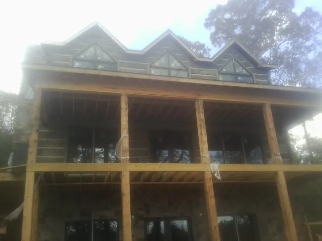 Dormers and porch framing on a large log home under construction — Roof Coating work by our crew in Whitharral