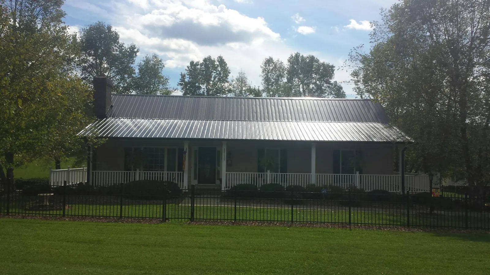 Gray metal roof on a brick ranch with a full width front porch — Gutter Guard Installation work by our crew in Whitharral