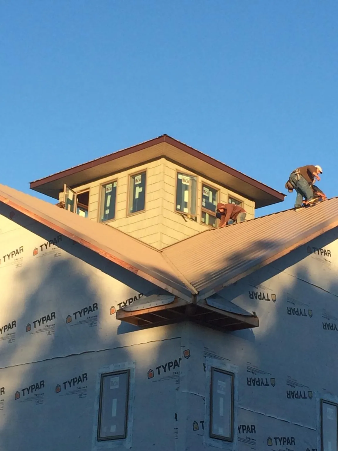 Roofers working around a rooftop cupola on a new metal roof at sunset — Roof Waterproofing in Whitharral by Roofing Brothers